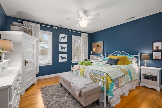 bedroom featuring visible vents, baseboards, light wood-style flooring, and a ceiling fan