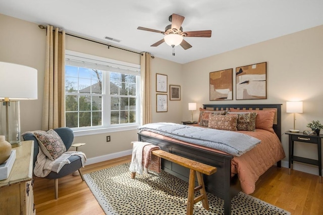 bedroom featuring light wood finished floors, visible vents, a ceiling fan, and baseboards