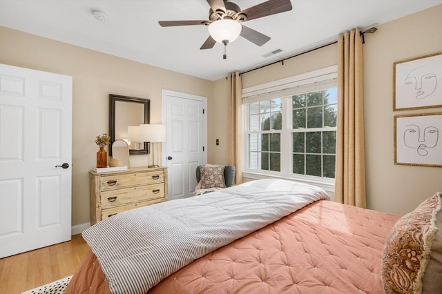 bedroom with a ceiling fan, wood finished floors, and visible vents