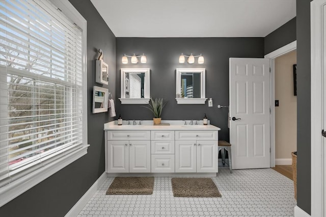 bathroom featuring a sink, baseboards, and double vanity