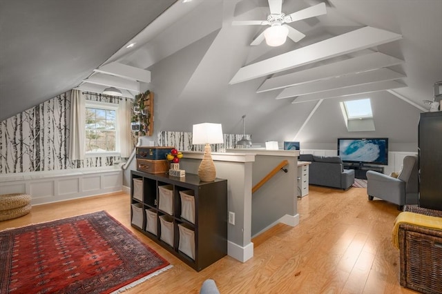 bonus room featuring a wainscoted wall, lofted ceiling with skylight, and light wood-style flooring