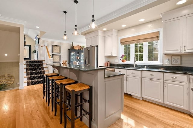 kitchen featuring a sink, a kitchen breakfast bar, high quality fridge, and crown molding