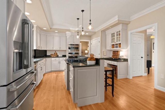 kitchen with stainless steel appliances, light wood-style flooring, a center island, and white cabinetry