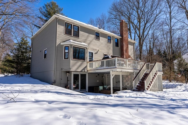 snow covered rear of property featuring stairway, a chimney, and a wooden deck