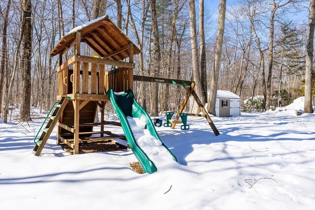 snow covered playground featuring a storage shed and a playground