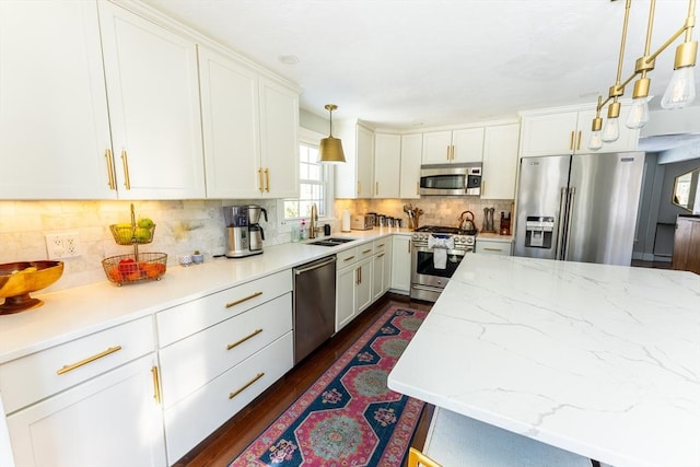 kitchen with pendant lighting, backsplash, appliances with stainless steel finishes, white cabinets, and a sink