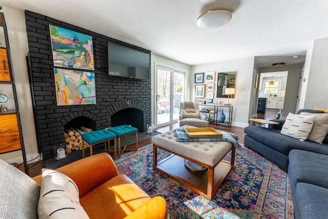 living room with a brick fireplace, wood finished floors, and baseboards