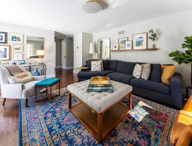 living room with arched walkways, dark wood-style flooring, visible vents, and baseboards