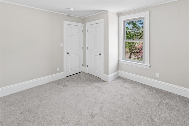unfurnished bedroom with crown molding, carpet floors, and baseboards