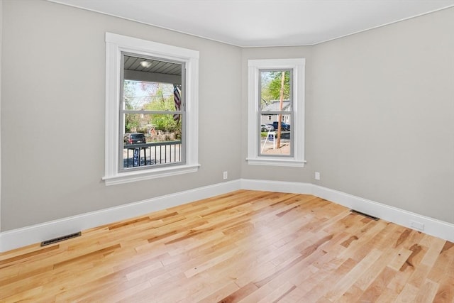 spare room featuring baseboards, wood finished floors, and visible vents