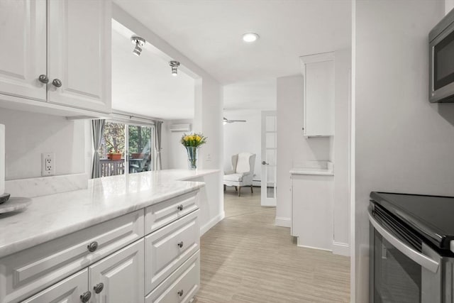 kitchen featuring stainless steel microwave, white cabinets, range with electric stovetop, light countertops, and recessed lighting