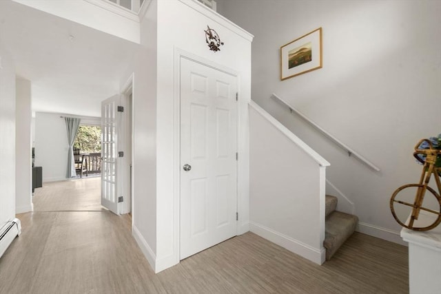 foyer with light wood-type flooring, stairs, a baseboard radiator, and baseboards