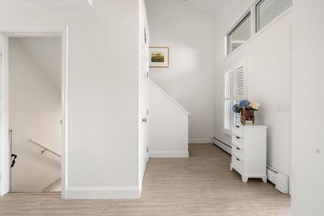 stairway featuring a baseboard radiator, wood finished floors, and baseboards