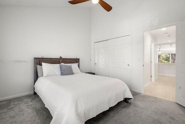 bedroom with carpet flooring, a ceiling fan, a closet, baseboards, and a towering ceiling