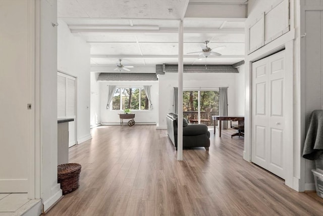 living area featuring ceiling fan, light wood finished floors, and beamed ceiling