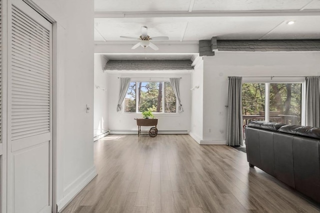 unfurnished living room featuring wood finished floors, baseboards, a ceiling fan, and a baseboard heating unit