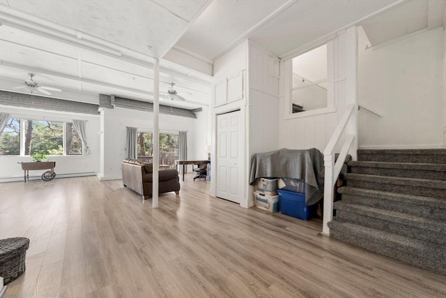 living area featuring ceiling fan, light wood-style flooring, stairs, and a baseboard heating unit