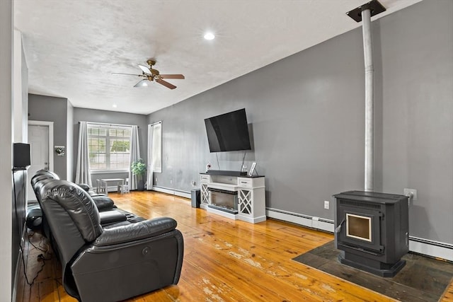 1185 Read St, Somerset, MA 02726 - living room featuring a baseboard radiator, ceiling fan, a wood stove, hardwood / wood-style flooring, and recessed lighting