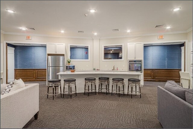 kitchen featuring appliances with stainless steel finishes, dark colored carpet, a breakfast bar, visible vents, and open floor plan