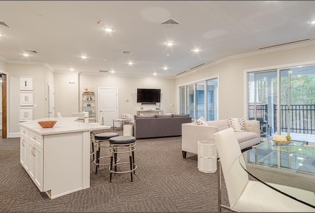 interior space with visible vents, dark carpet, a kitchen bar, and crown molding