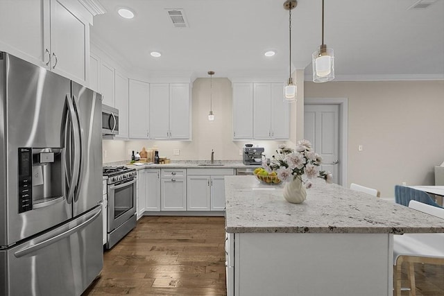 kitchen featuring a kitchen bar, white cabinets, appliances with stainless steel finishes, and a kitchen island
