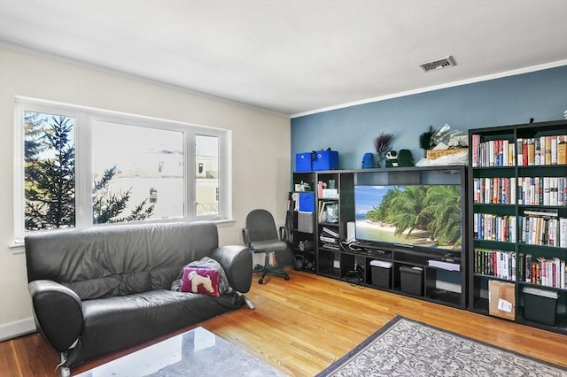 sitting room featuring crown molding, wood finished floors, visible vents, and plenty of natural light