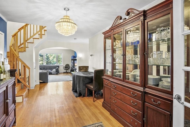 interior space featuring light wood-style floors, a chandelier, arched walkways, and stairs
