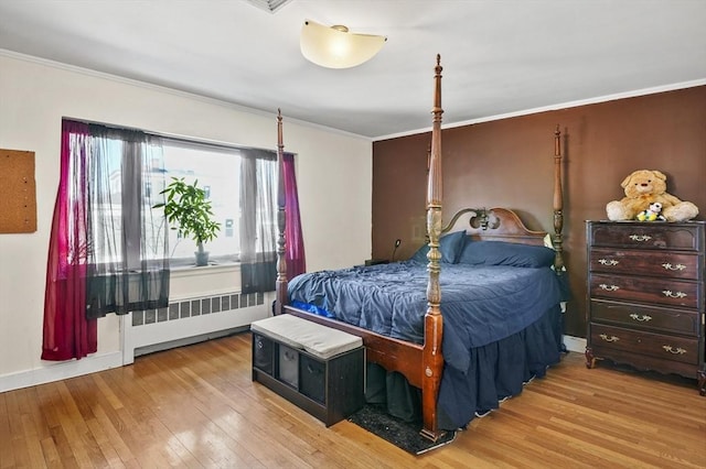 bedroom with radiator heating unit, hardwood / wood-style flooring, baseboards, and ornamental molding