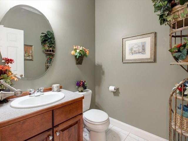 bathroom with toilet, vanity, and baseboards