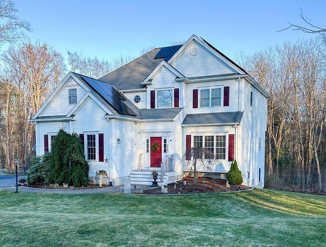 view of front facade featuring a front lawn and roof mounted solar panels