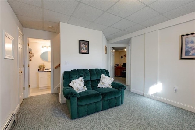 carpeted living room featuring a drop ceiling, a baseboard radiator, and baseboards