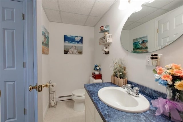 bathroom with a baseboard heating unit, toilet, tile patterned floors, vanity, and a paneled ceiling