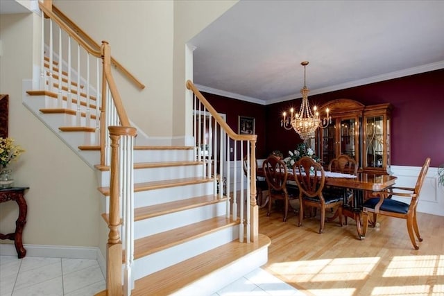 dining space featuring crown molding, baseboards, a chandelier, stairs, and wood finished floors