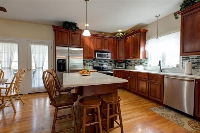 kitchen with decorative backsplash, light countertops, light wood-style floors, and stainless steel appliances