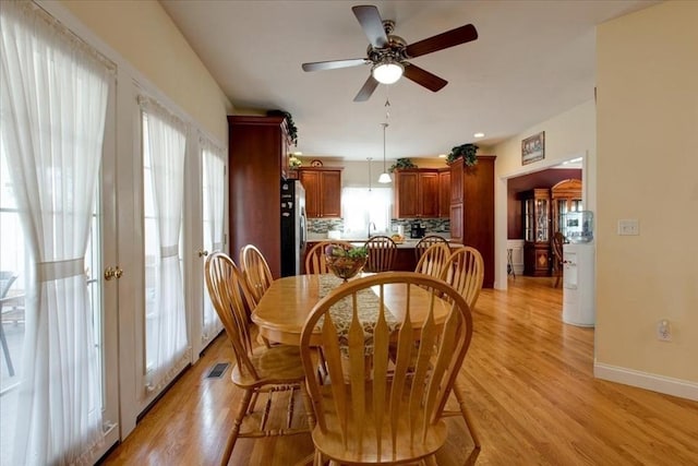 dining room featuring a ceiling fan, visible vents, light wood-style floors, and baseboards