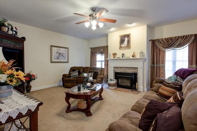 living area featuring baseboards, a brick fireplace, ceiling fan, and carpet flooring