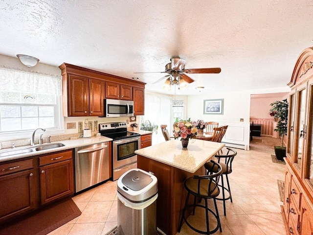 93 Mccracken Rd, Millbury, MA 01527 - kitchen with stainless steel appliances, a sink, light countertops, ceiling fan, and a kitchen breakfast bar
