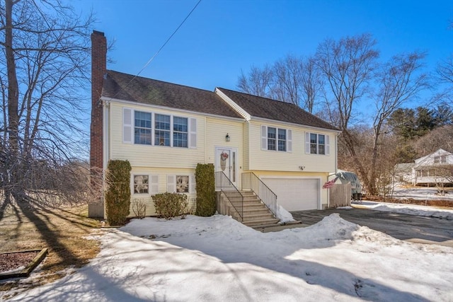 split foyer home with aphalt driveway, a chimney, and a garage