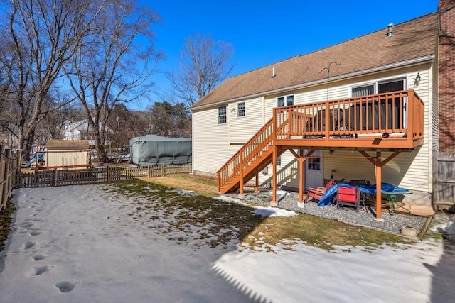 snow covered house featuring fence, stairway, and a wooden deck