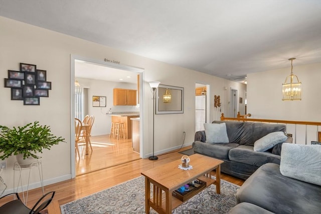 living room with light wood finished floors, baseboards, and a chandelier