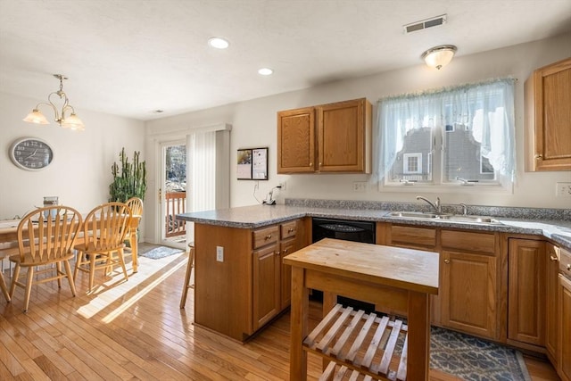 kitchen featuring visible vents, light wood-style flooring, a breakfast bar, a peninsula, and a sink