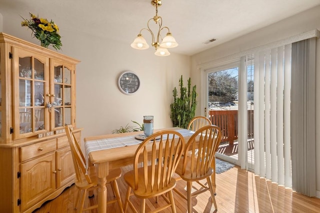 dining space featuring visible vents, light wood-style flooring, and an inviting chandelier