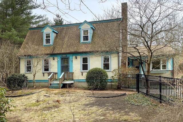 view of front facade with a chimney, fence, and roof with shingles
