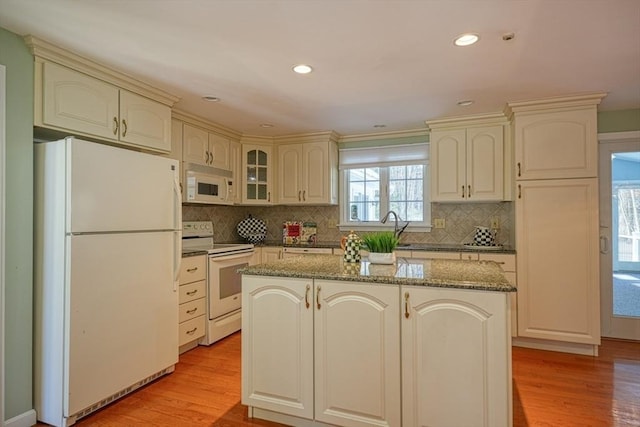 kitchen featuring white appliances, light hardwood / wood-style flooring, a center island, and decorative backsplash