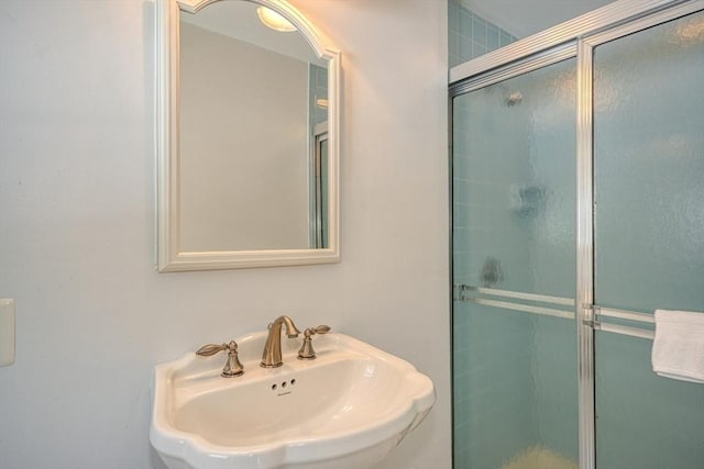 bathroom featuring a shower with door and sink