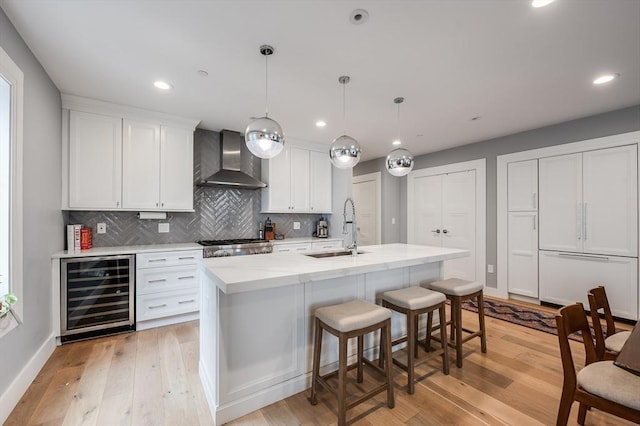 510 Dorchester Ave Unit 2R, Boston, MA 02127 - kitchen featuring wine cooler, wall chimney range hood, a sink, white cabinets, and decorative backsplash
