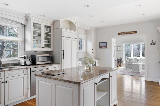 kitchen with open shelves, plenty of natural light, stainless steel appliances, and a sink