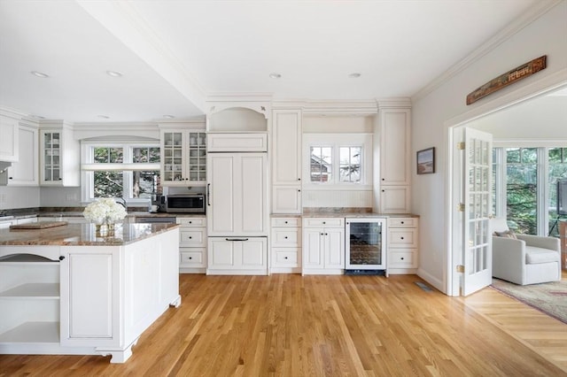 kitchen with stainless steel microwave, a healthy amount of sunlight, open shelves, and wine cooler