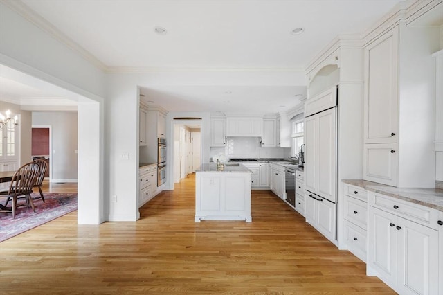 kitchen with plenty of natural light, an inviting chandelier, light wood-style floors, and crown molding