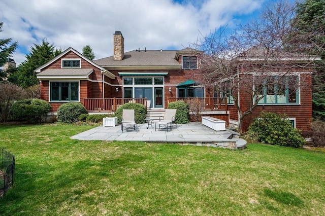 rear view of property featuring a lawn, a chimney, and a patio